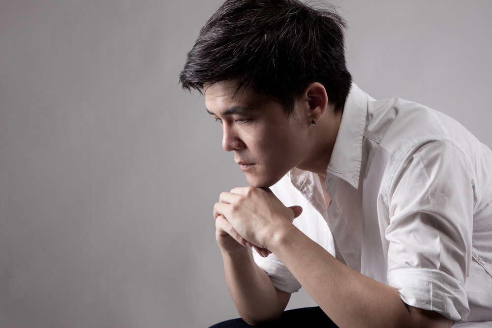 A man in white polo shirt looking sad due to mental health problem.