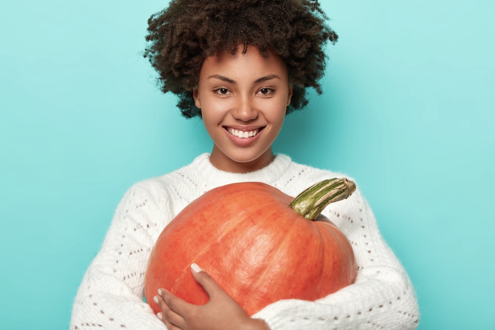 A woman hugging a pumpkin during Thanksgiving