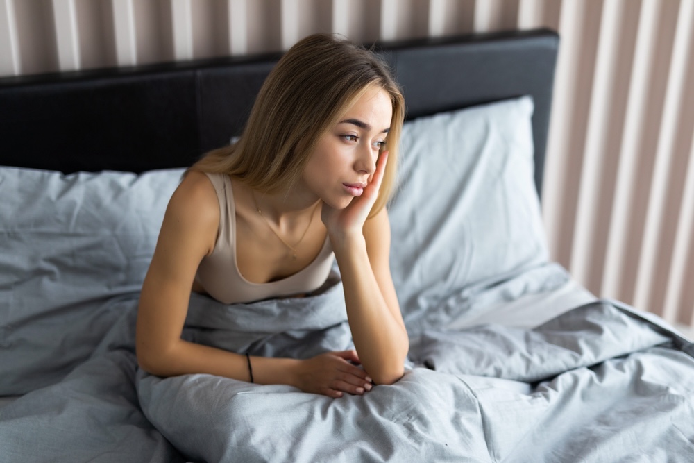 Woman in bed feeling withdrawal symptoms and cravings for drugs