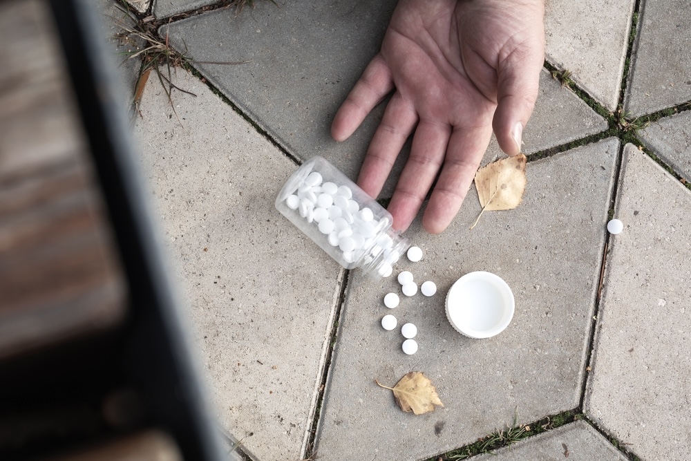 Bottle of fake oxycodone pills drops to the ground with a man’s hand in the foreground