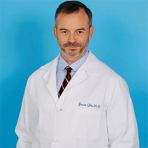 Dr. Jason Giles M.D. wearing white coat in blue background