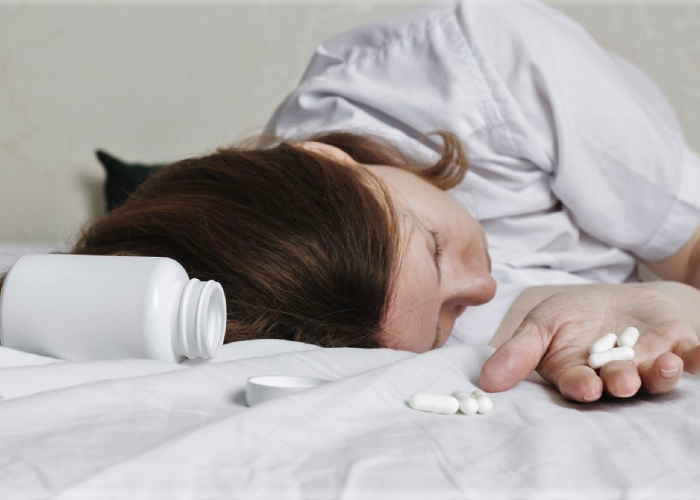 Woman in bed holding medication pills