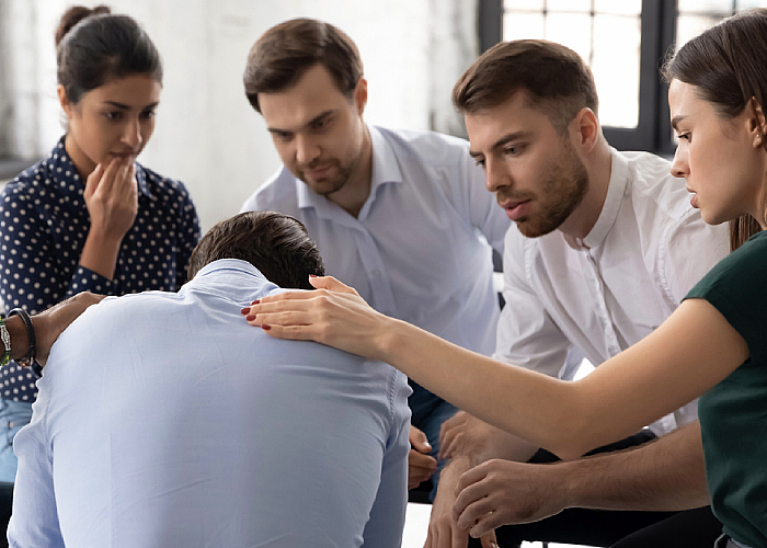 Group of people consoling their male friend