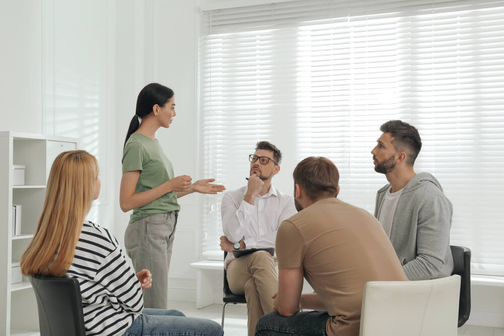 Woman with black hair explaining in a group meeting at a detox in Los Angeles