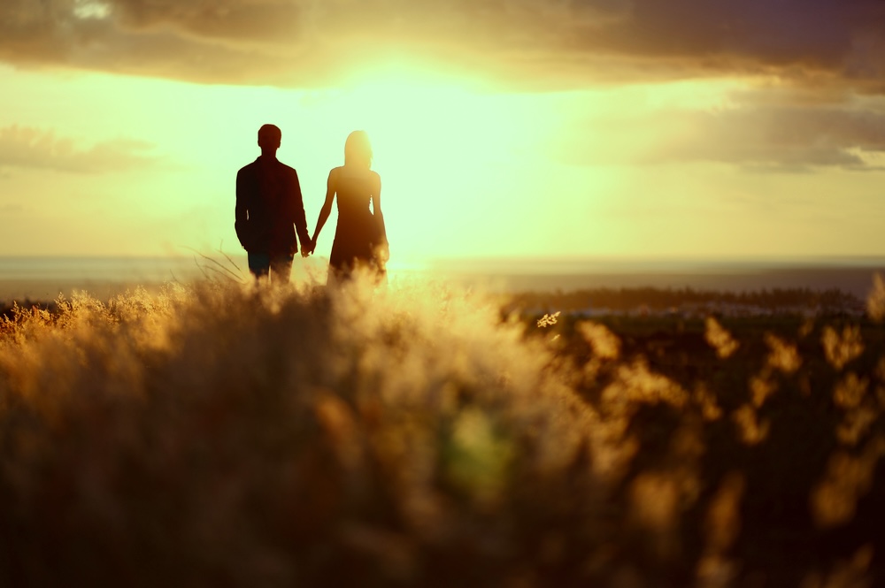 Couple holding hands watching sunset