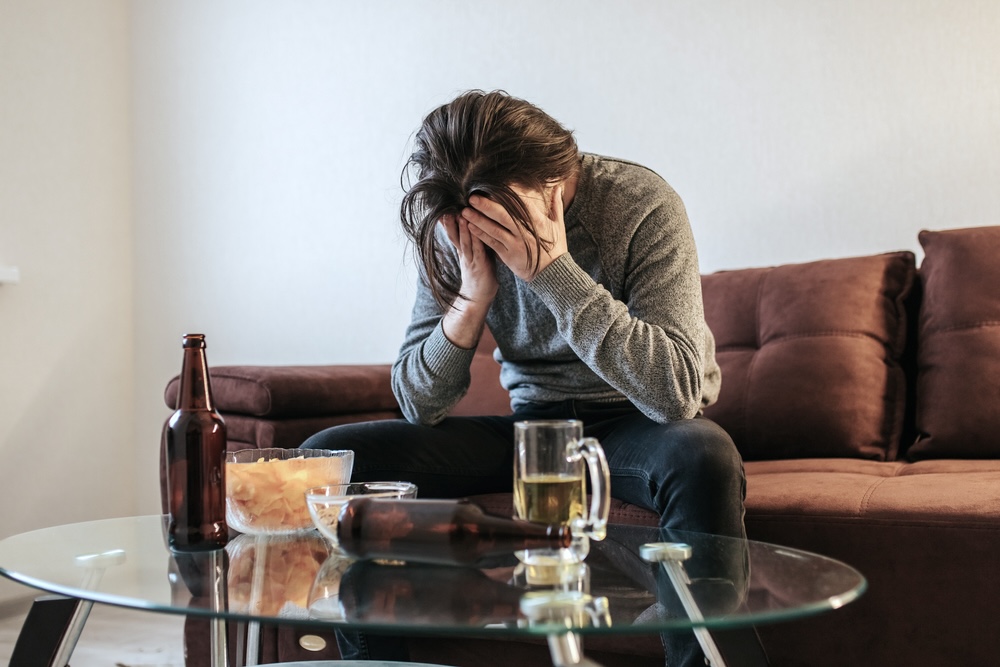 A man suffering from alcoholism in front of alcoholic drink