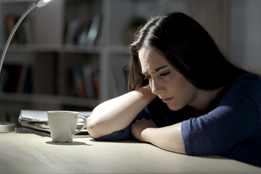 A woman suffering from mental health on a desk at night in the living room at home