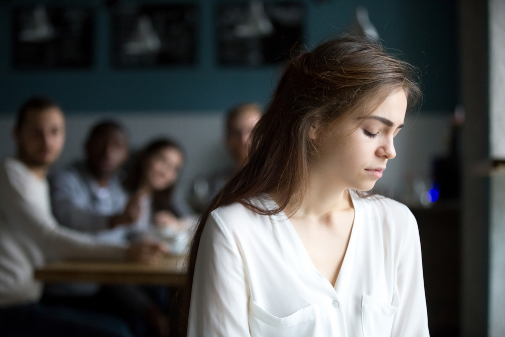 A woman in white shirt alone while the family are at the back