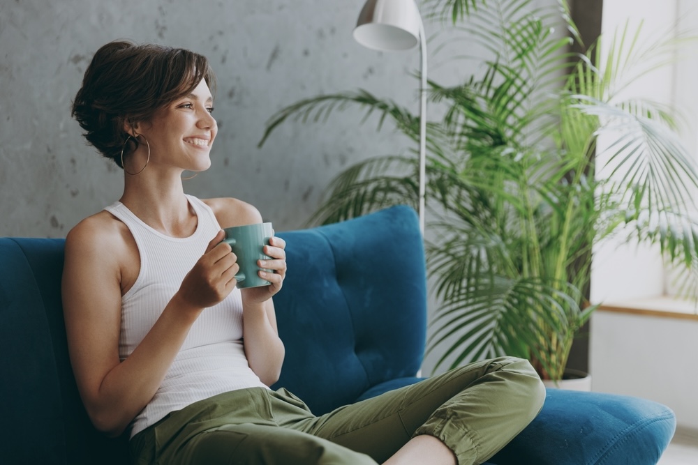 Woman sitting on a residential treatment facility living area drinking tea