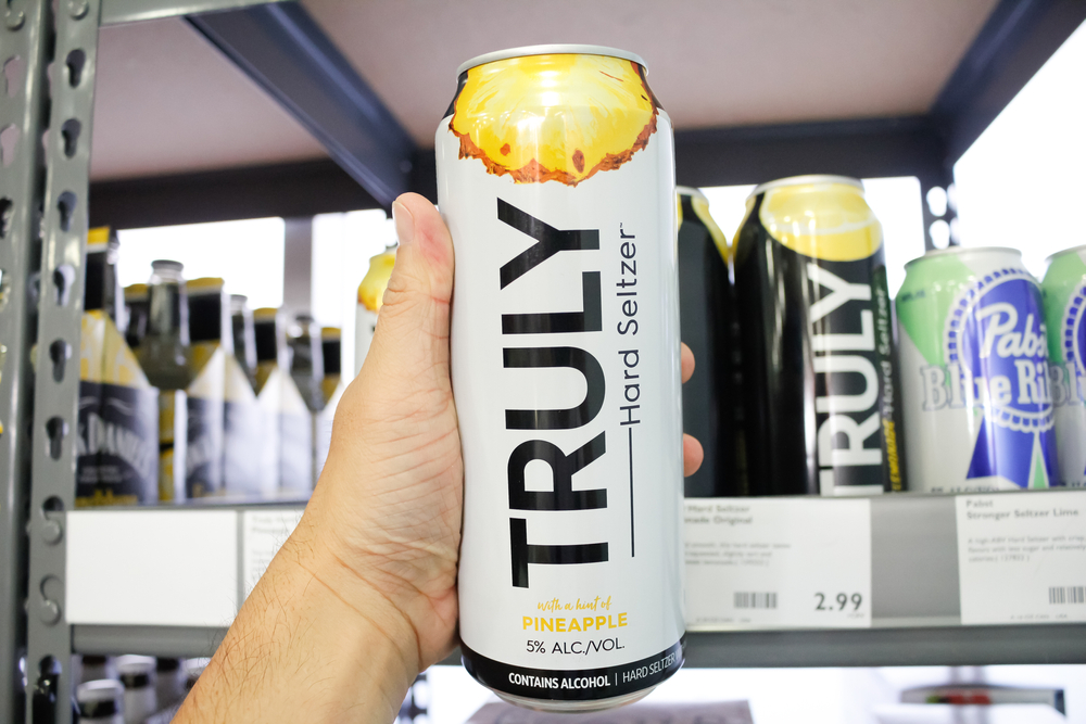 A hand holding a can of Truly in supermarket