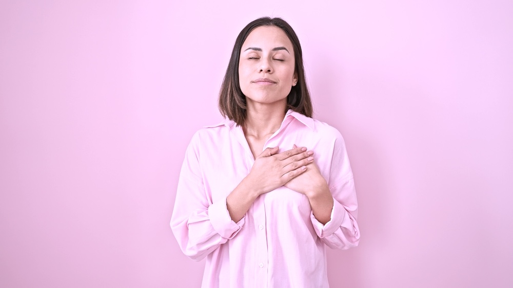 Woman puts her hands over her heart while praying to heal depression and anxiety