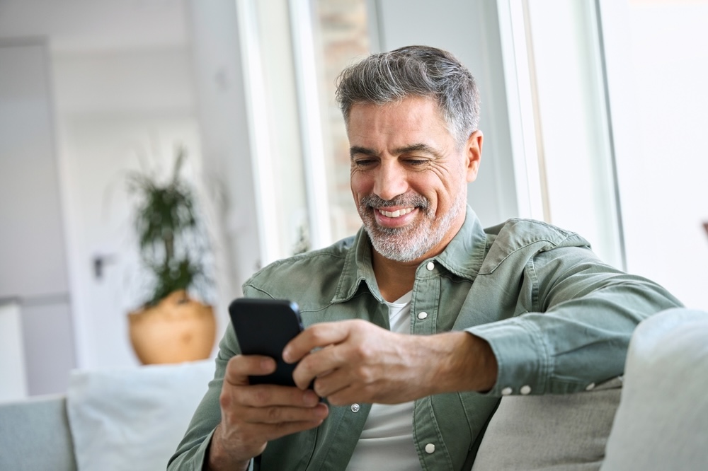 Elderly man reading from his phone a sobriety quote sent by a friends